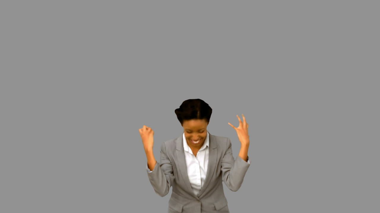 Pretty businesswoman raising arms on grey screen