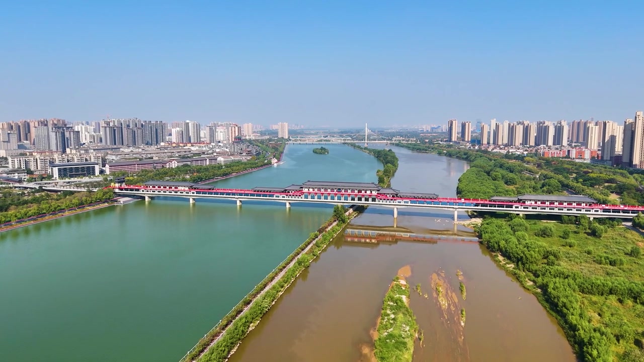Vista drone che attraversa il fiume Weihe a Xi'an, provincia dello Shaanxi, Cina. Ponte tradizionale sotto la luminosa luce solare diurna, circondato da paesaggi scenografici e acque calme.