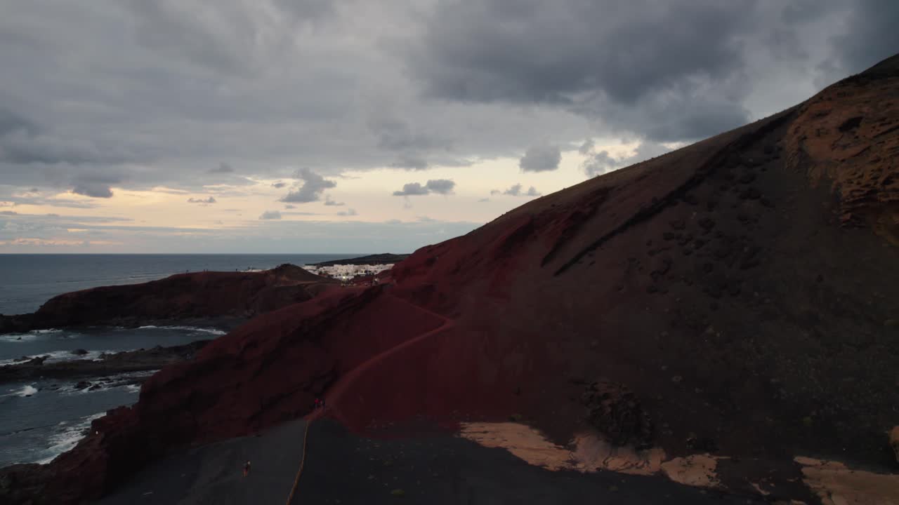 vuelo de drones hacia atrás sobre las altas montañas y una playa de arena negra en la isla volcánica de lanzarote en el océano atlántico
