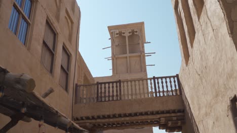 Wind-Tower-On-Traditional-Buildings-In-Historical-Neighborhood-Of-Al-Fahidi,-Dubai-UAE---Handheld,-Low-Angle