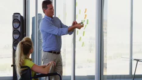 Side-view-of-Caucasian-female-and-male-executive-discussing-over-sticky-notes-in-the-office-4k