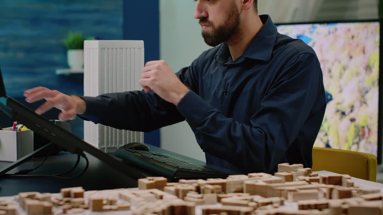 Close up of man working on computer with building model