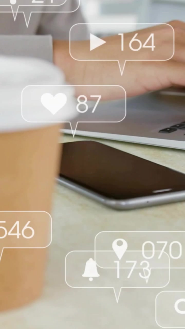 Vertical video: Male arm reacting to social alerts, typing on laptop with coffee as likes climbing