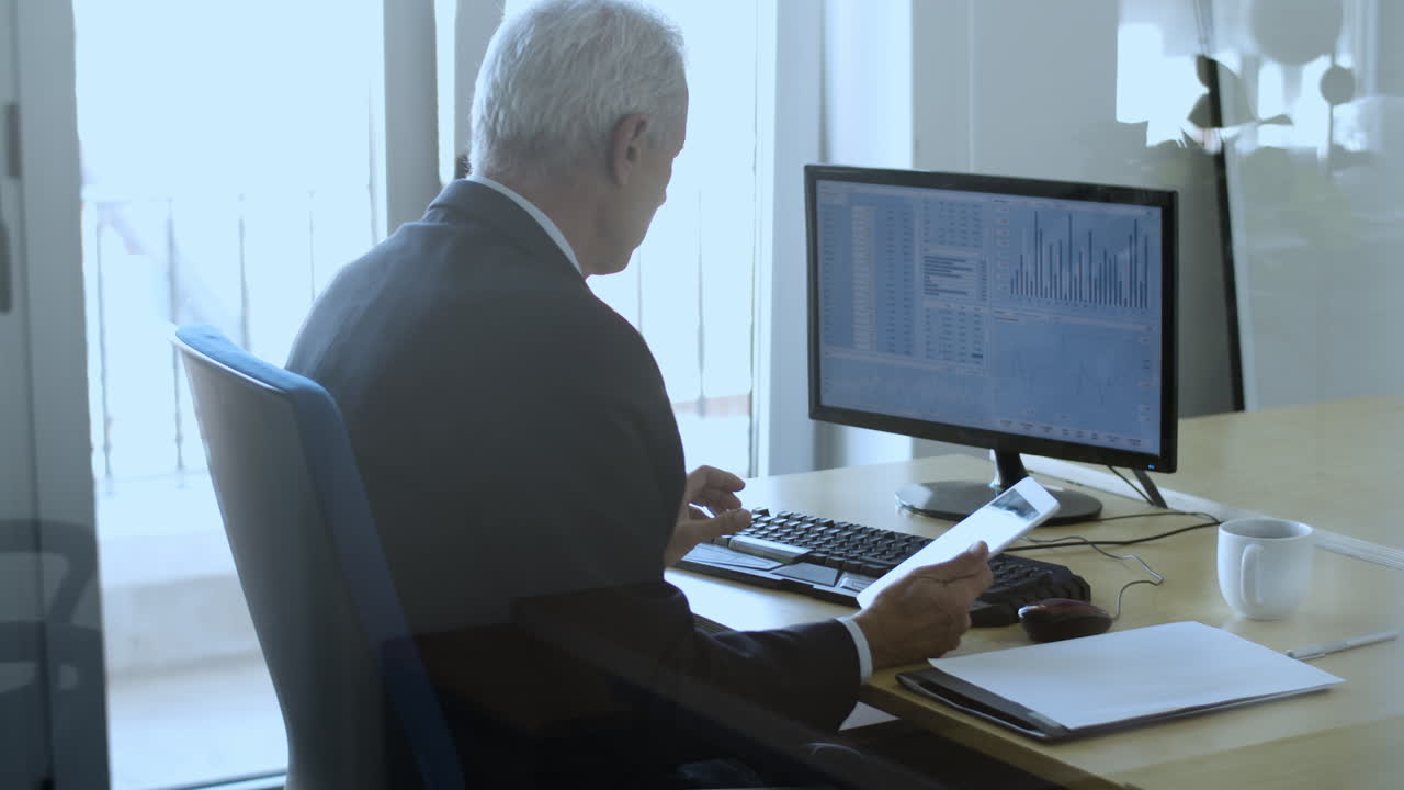 Focused mature male trader working with the computer