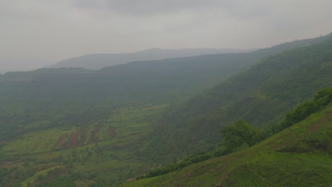 a drone glides over the lush green mountains of panchgani, maharashtra, as monsoon mist weaves through the valleys and treetops, creating a serene and mystical atmosphere over the western ghats