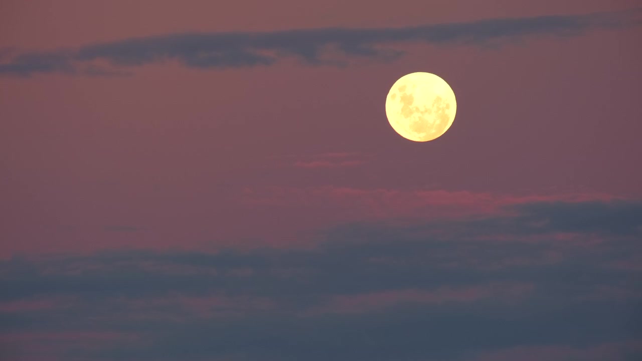 Lua cheia amarelada no céu crepuscular com algumas nuvens finas e esparsas, teleobjetiva