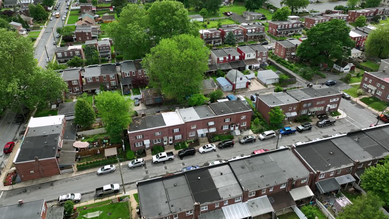 Row of houses and homes in american town. Red brick buildings in green idyllic suburb neighborhood. Aerial top down shot. Cars on street.
