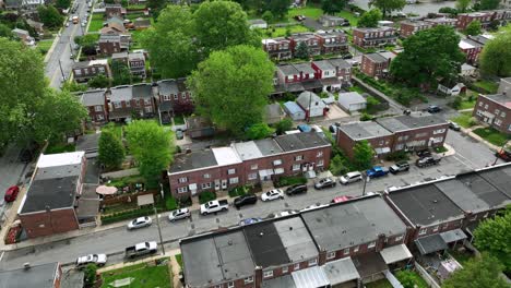 row of houses and homes in american town. red brick buildings in green idyllic suburb neighborhood. aerial top down shot. cars on street.