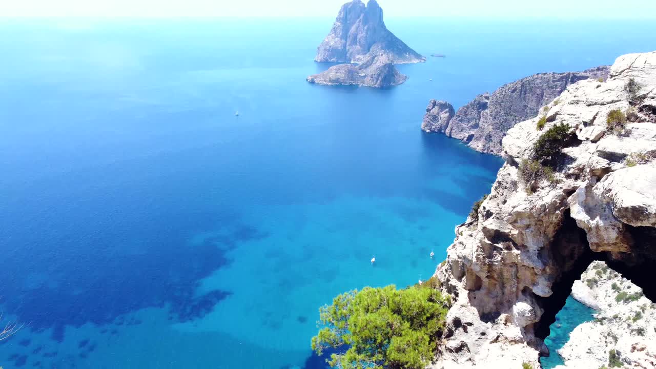 Flight over edge of cliff, island strong sun blue water
Breathtaking aerial view flight tilt up drone footage
of cliff edges hike Es Vedra Ibiza summer 2022