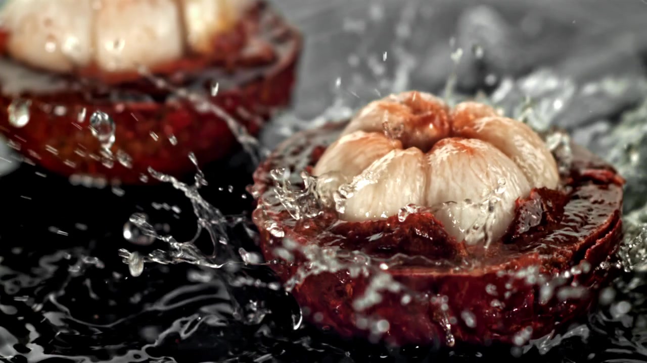 Close-up van verse mangosteenhelften met spattend water