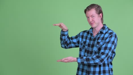 portrait of caucasian man smiling and showing copy space shot against green studio background