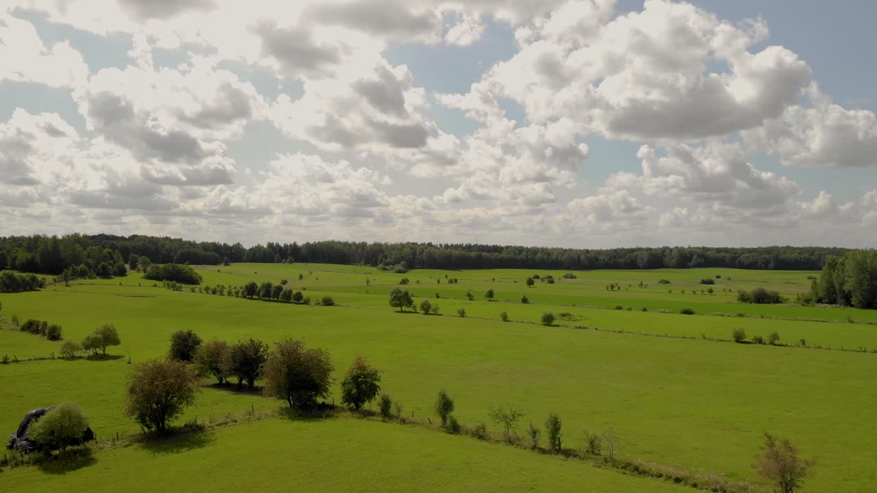 imágenes aéreas sobre pradera verde, el cielo es azul y nubes blancas, debajo hay hierba verde, árboles y algunos caminos, este de polonia