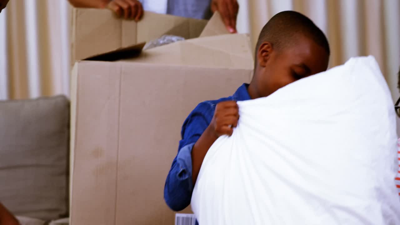 Parents and kids opening cardboard boxes in living room