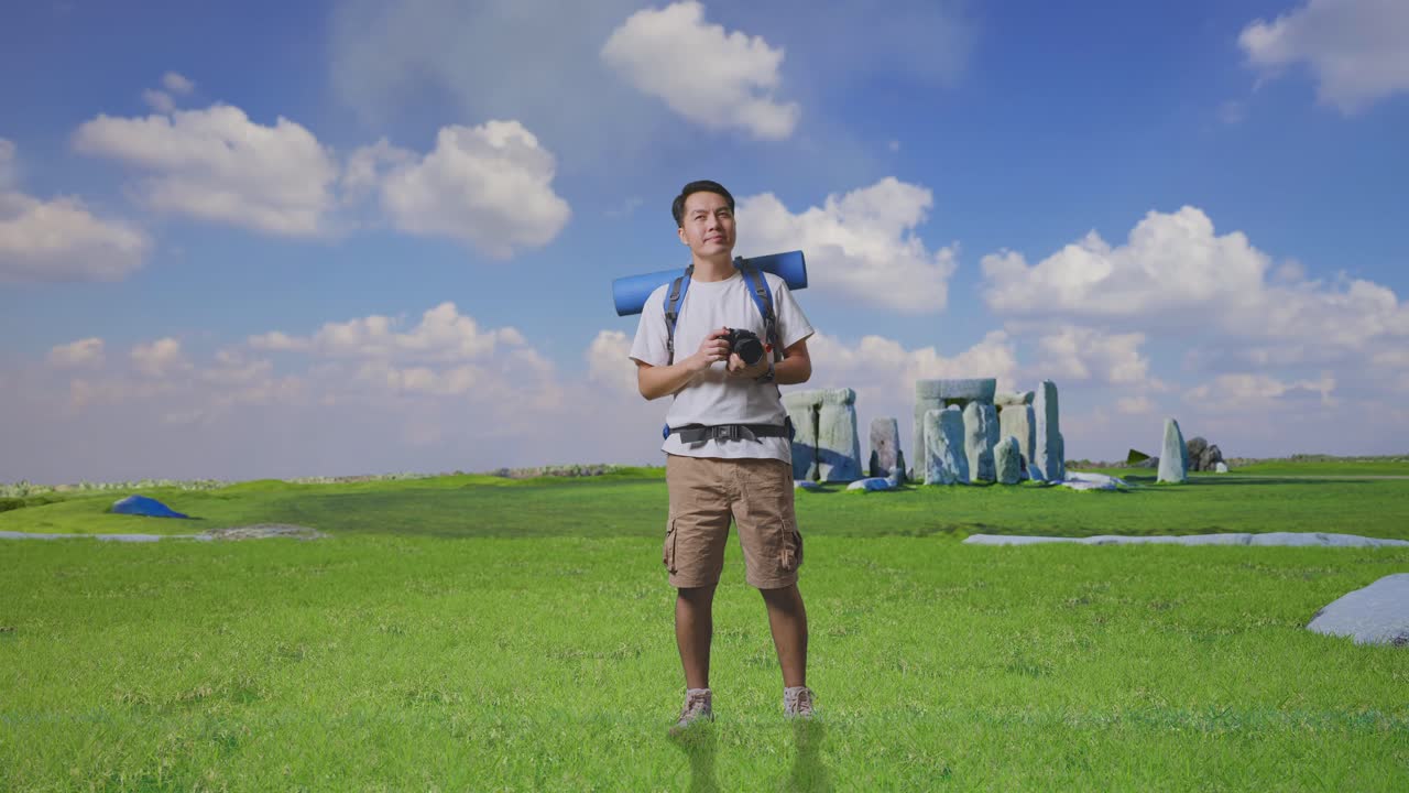 Full Body Of Asian Male Hiker With Mountaineering Backpack Holding A Camera In His Hands Then Looking Around While Traveling In Stonehenge