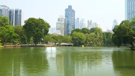lush park with water fountain and the backdrop of tall buildings in bangkok city