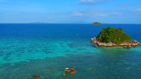 Vista-Superior-De-Una-Playa-Azul-Clara-Con-Una-Pequeña-Isla-A-Un-Lado