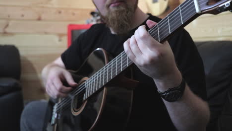 bearded man playing black acoustic guitar, finger style medium shot