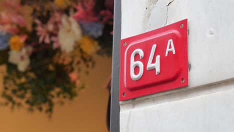 close-up of house number 64a on a red sign