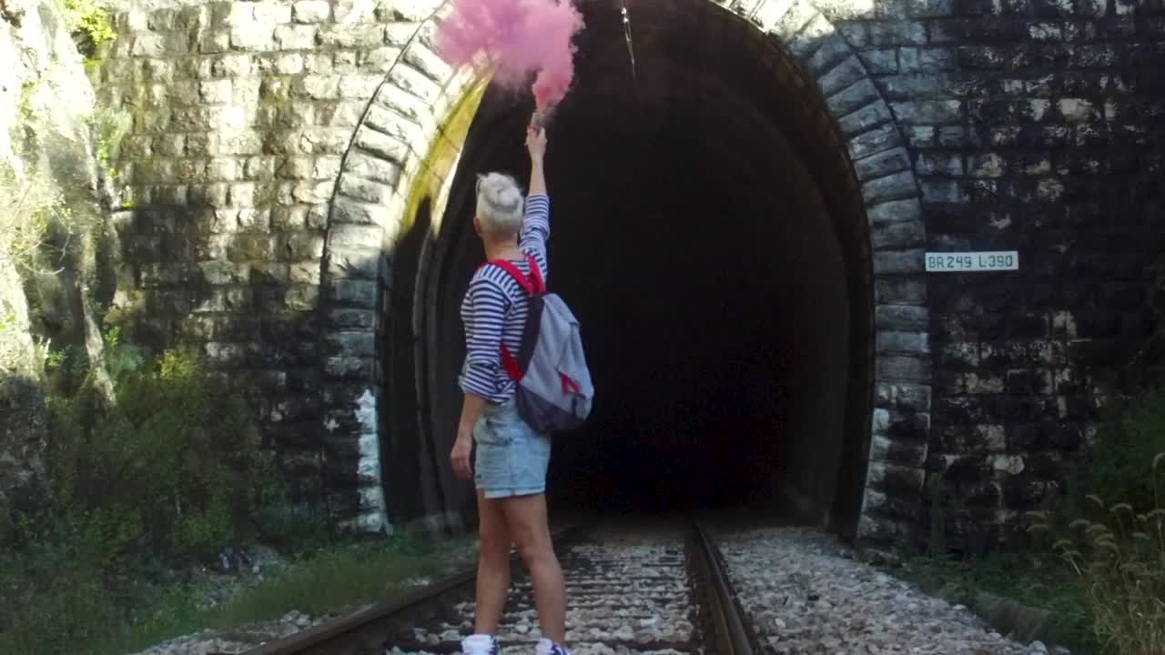 Donna che rilascia fumo rosa in un tunnel ferroviario