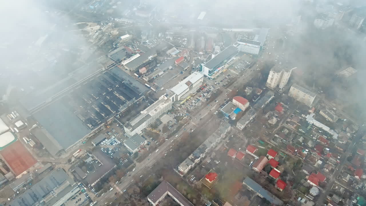 Aerial drone view of Chisinau through the clouds. Panorama view of multiple buildings, roads with moving cars and bare trees. Moldova