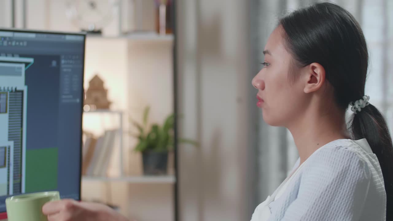 自宅のデスクトップで家を設計中にコーヒーを飲むアジア人女性エンジニアのクローズアップ。サイバーゲームの家設計と装飾。
