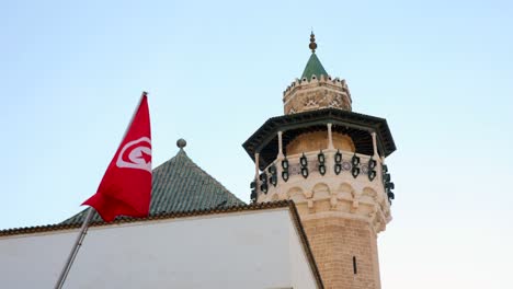 low angle view of a tunisia flag with the facade of a tower and a wall as background