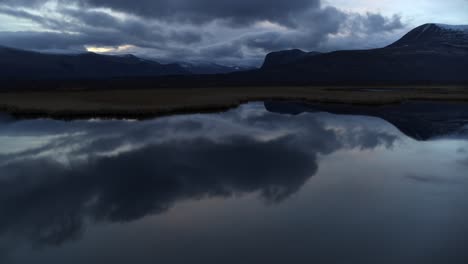 aerial forward over reflective lake in lapland, sweden in the night, cinematic