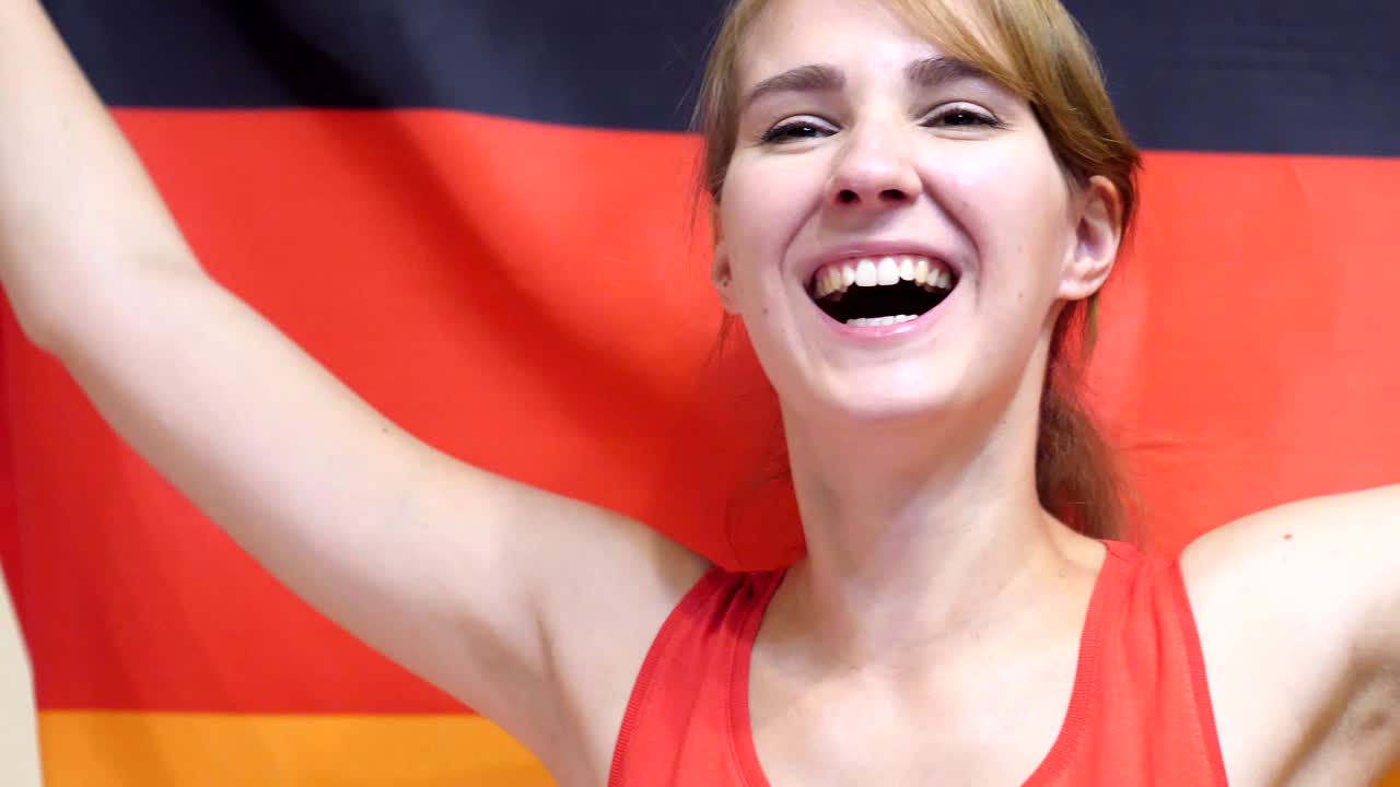 Giovane donna tedesca festeggia tenendo la bandiera della Germania al rallentatore
