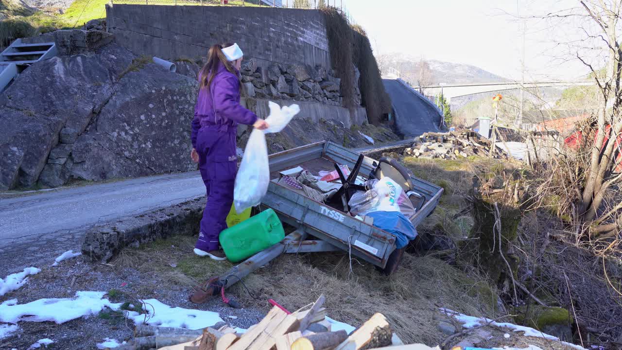 Woman places plastic removed from Norway fjord into trailer for recycling