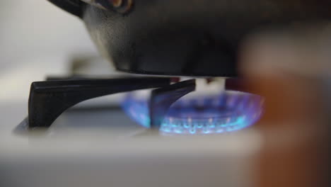 pan is put down on top of a blue flame from a gas-powered stove