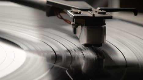 dropping stylus needle on vinyl record playing with disc rotating close up