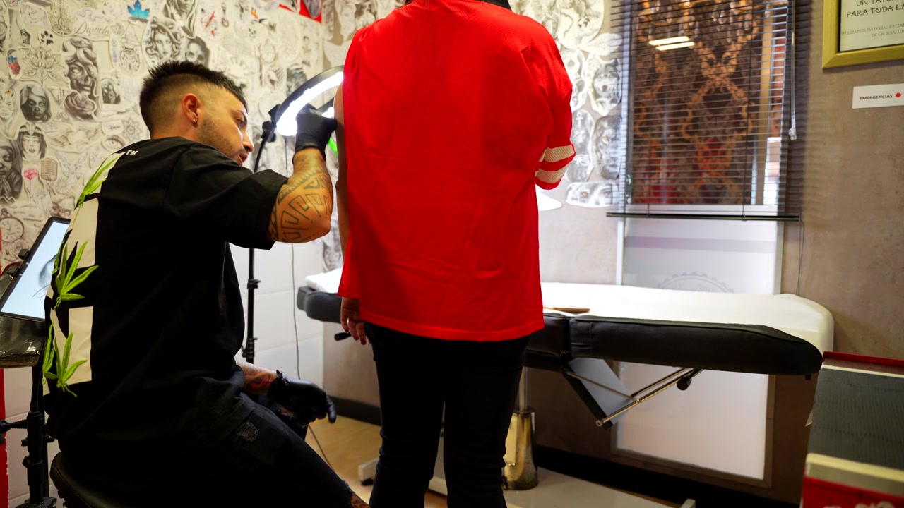 Tattoo artist appears on scene shaving the arm of his customer to start tattooing