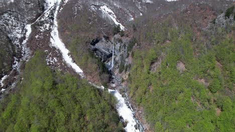 waterfall of rragam in albanian valbona valley with ice water melting from snow in mountains