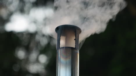 Close-view-of-smoke-comes-out-of-a-stove-chimney-in-the-forest