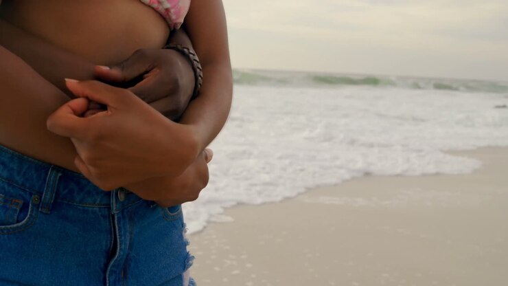 Mid section of African American couple embracing each other on the beach 4k