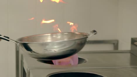 cook prepares the vegetables on a burning frying pan