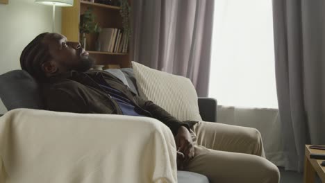 unhappy or depressed man at home sitting on sofa in lounge