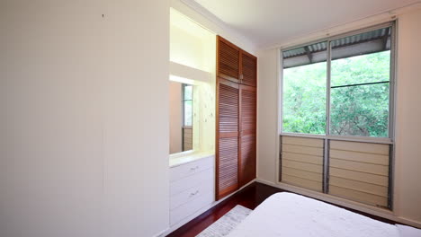 el retroceso establece un elegante dormitorio principal tropical al final del pasillo con pisos de madera.