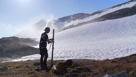 static shot of mountaineer attaching skins to his skis an early summer morning in the mountains