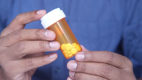 persona que sostiene una botella de pastillas