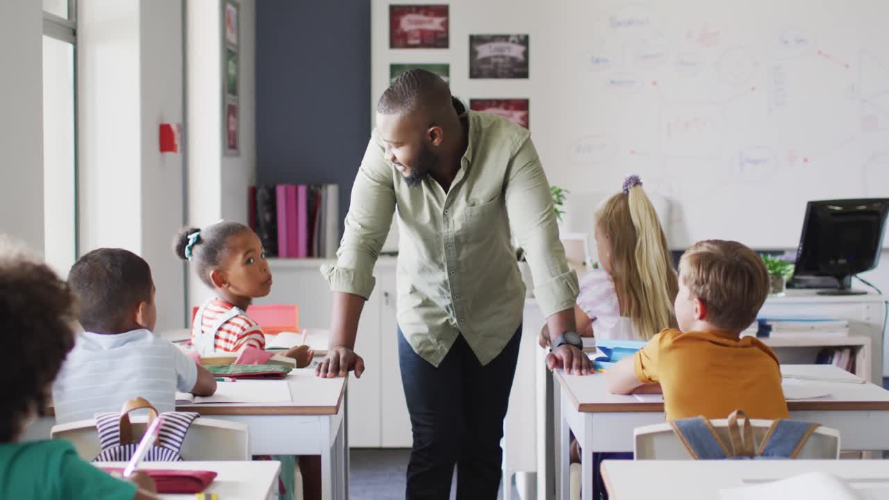 Video of happy african american male teacher during lesson with class of diverse pupils