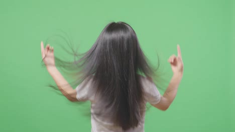 back view of a woman fluttering her long black and blond straight healthy hair in the green screen background studio