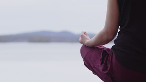 Meditating-European-lady-sitting-down-relaxed-overlooking-lake,-copy-space-left