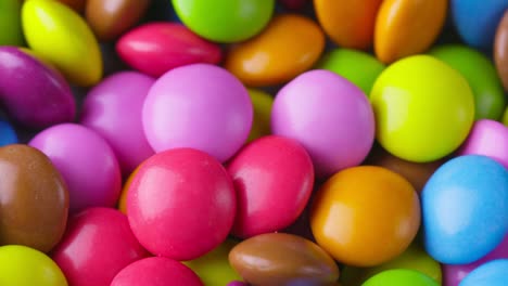 slow motion close-up of round colorful chocolate candies, dragee. rotation and fall multicolored chocolate candies