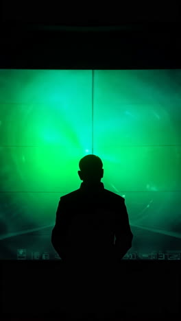 silhouette of a man in front of a green futuristic digital screen