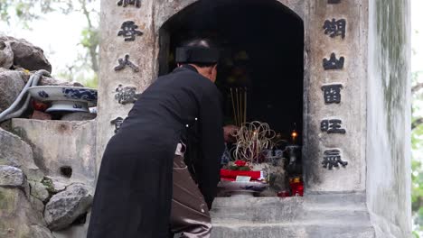 man lighting incense at a shrine in hanoi