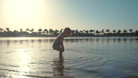Sweet-active-toddler-falling-into-seawater-at-summer-coastline.