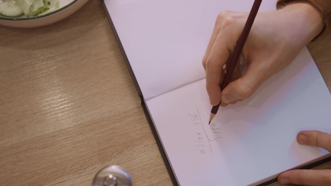 Primo piano della mano di una donna che scrive equazioni matematiche a matita su carta bianca, con illuminazione soffusa ed espressione naturale. La scena mostra la donna che tiene fermo un quaderno aperto mentre forma simboli precisi.