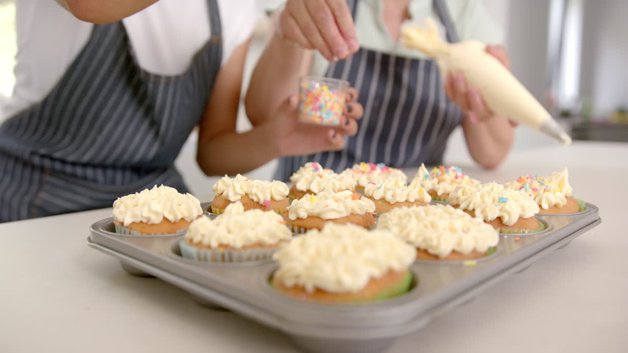 Decorating cupcakes with sprinkles, two people enjoying baking activity at home