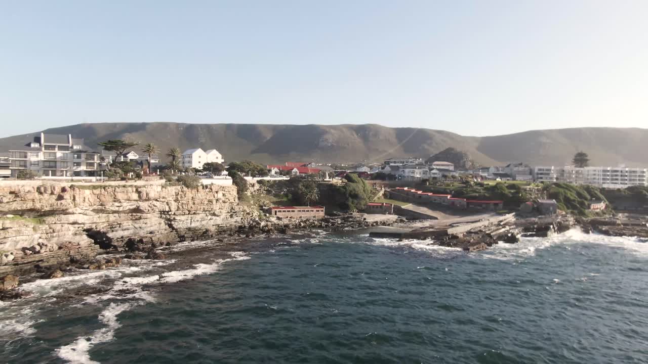 아름다운 건축물이 있는 섬의 바위 해안을 부서지는 파도 - 공중 촬영